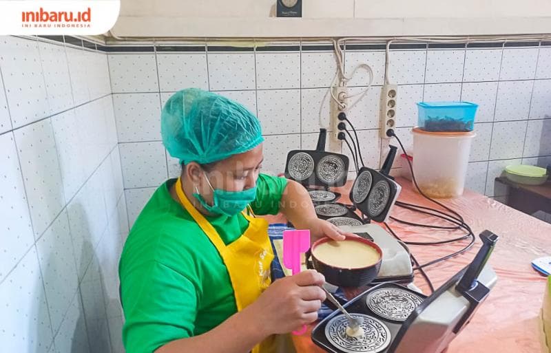 Seorang pegawai sedang mencetak kue semprong di ruang produksi. (Inibaru.id/Fitroh Nurikhsan)
