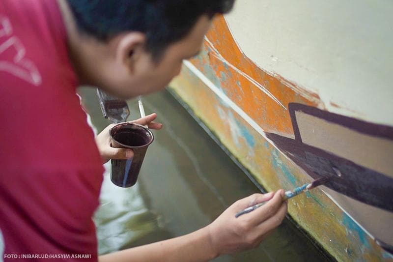 Dengan penuh ketelitian, pelukis mengoleskan kuasnya di salah satu sudut di Sendang Kamulyan, Dukuh Pranak, Desa Lau, Kecamatan Dawe, Kabupaten Kudus.