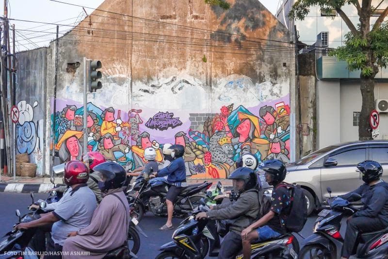 Mural berbasis cerita rakyat di tembok pembatas jalan raya di salah satu sudut di pusat kota Kudus menjadi tontonan para pengendara motor yang melintas.