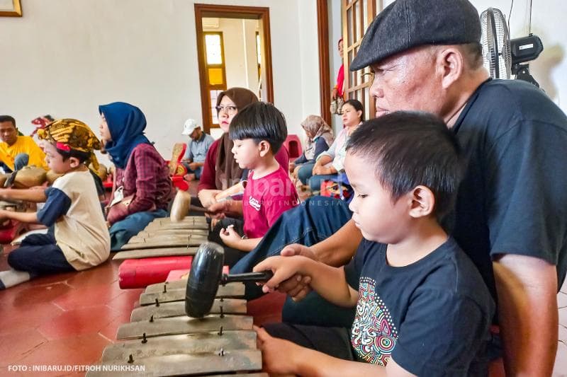 Orang tua turut mendampingi anaknya memainkan alat musik gamelan.