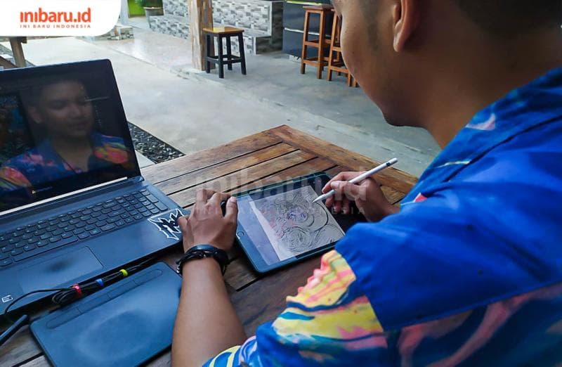 Burhan menggunakan laptop, pen tablet dan ipad untuk menggarap pesanan ilustrasi digital dari klien.&nbsp;(Inibaru.id/ Rizki Arganingsih)