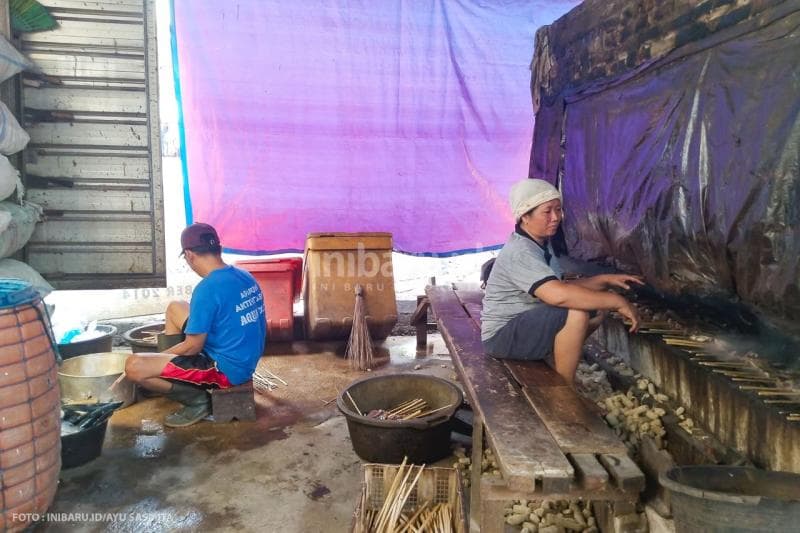 Titik dan Agus, pasangan istri-suami asal Desa Cabean tengah mengolah ikan asap di sebuah ruangan bercerobong di depan rumahnya.