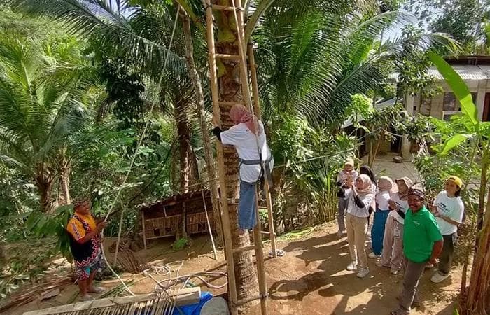 Wisatawan naik pohon kelapa untuk menderes nira di Desa Wisata Hargotirto. (Radarjogja/Hendri Utomo)