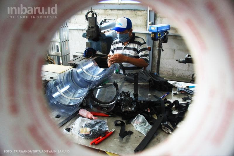 Pekerja menyiapkan bahan yang digunakan dalam pembuatan face shield.