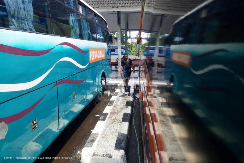 Sopir bus mencuci kendaraanya karena tidak ada penumpang yang datang ke Terminal Penggaron.