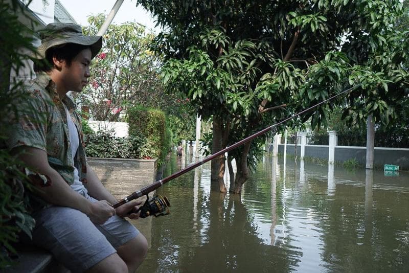 Anak Ahok tampak memancing di teras rumahnya saat banjir rob. (Instagram/nachoseann)<br>