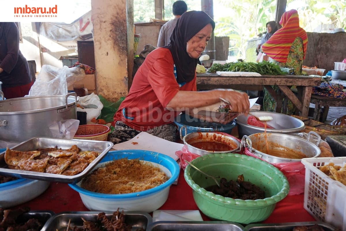 Maryatun, salah seorang penjual nasi krempyeng, sedang membungkus nasi krempyeng. (Inibaru.id/ Ida Fitriyah)