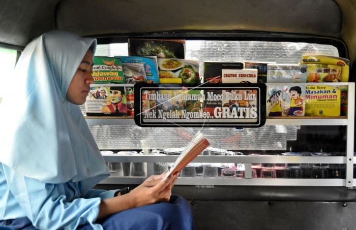 Salah seorang penumpang sedang membaca buku di perpustakaan angkot milik Sudaryanto. (Antara Foto/Aditya Pradana Putra) 
s