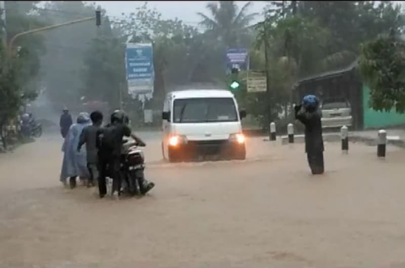 Warga mencoba melewati jalan raya Semanu, Gunungkidul, DIY, yang digenangi banjir sebagai dampak Badai Cempaka beberapa waktu lalu. (iNews/Kismaya Wibowo)