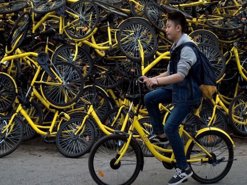 Seorang pria di Beijing, Tiongkok, melewati tumpukan sepeda yang teronggok begitu saja. (Sky News)